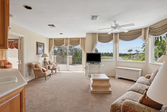 living room featuring a textured ceiling, light colored carpet, and ceiling fan