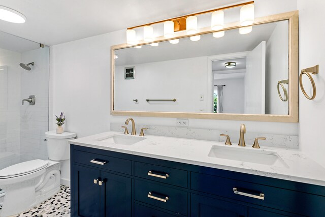 bathroom with tiled shower, vanity, and toilet