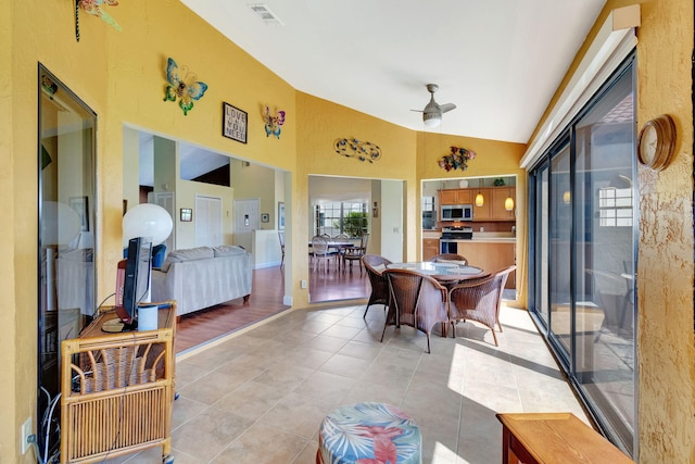 dining room with light hardwood / wood-style flooring, ceiling fan, and high vaulted ceiling