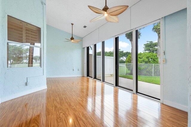 unfurnished room with a wealth of natural light, light hardwood / wood-style flooring, and vaulted ceiling