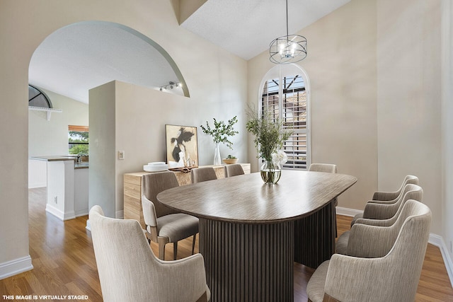 dining space featuring light wood-type flooring, a chandelier, and vaulted ceiling