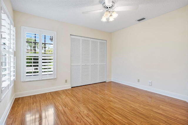 unfurnished bedroom with a textured ceiling, light hardwood / wood-style floors, ceiling fan, and a closet
