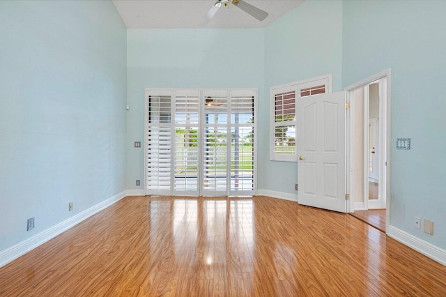 empty room with a towering ceiling, light hardwood / wood-style floors, and ceiling fan