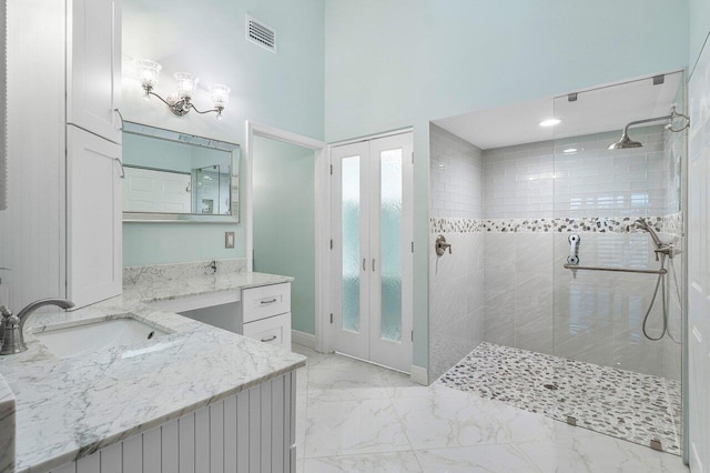 bathroom with a towering ceiling, french doors, vanity, and tiled shower