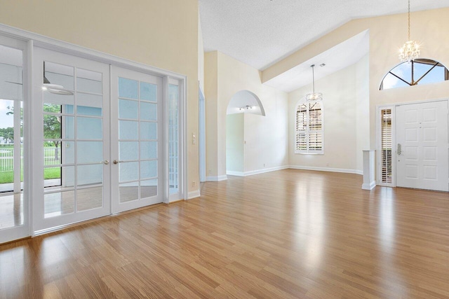 entryway with light hardwood / wood-style floors, lofted ceiling, a textured ceiling, and a notable chandelier