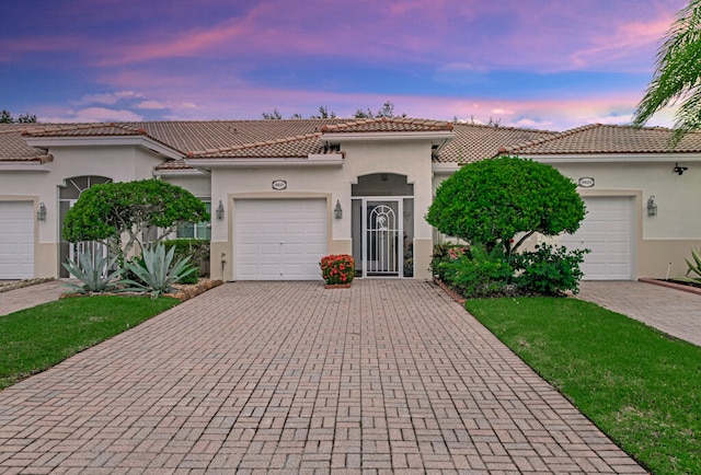 mediterranean / spanish-style home featuring a yard and a garage