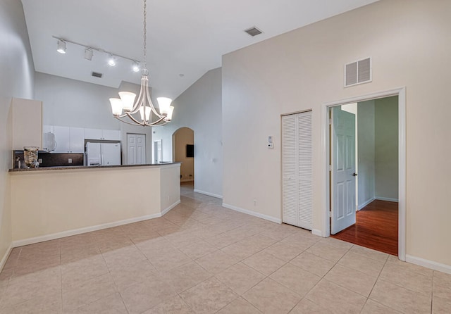 interior space with light tile patterned floors, an inviting chandelier, and a high ceiling