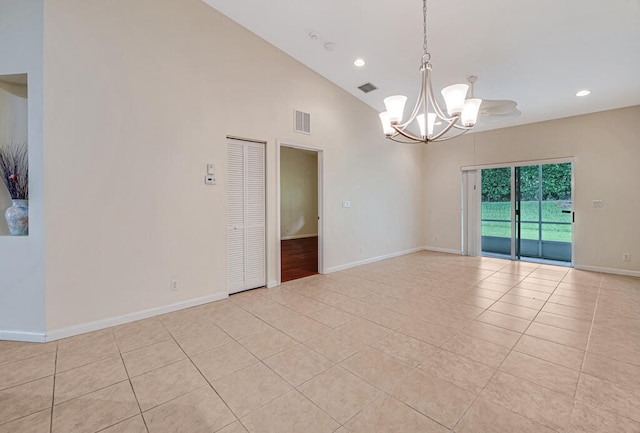 tiled empty room featuring high vaulted ceiling and a notable chandelier