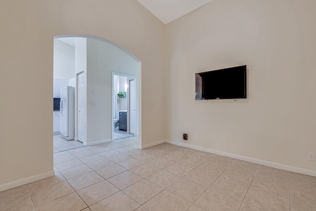 tiled empty room featuring high vaulted ceiling