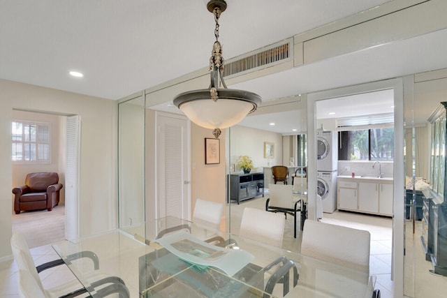 tiled dining area featuring sink and stacked washing maching and dryer