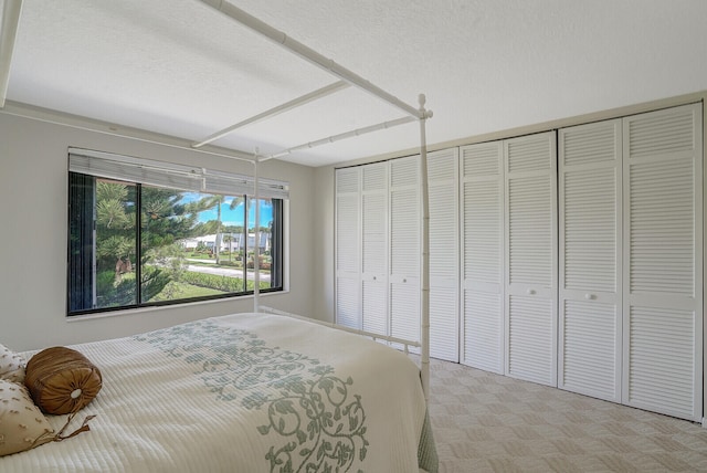 bedroom with multiple closets and a textured ceiling