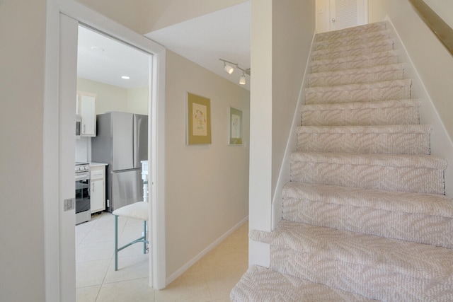 staircase with tile patterned floors and rail lighting