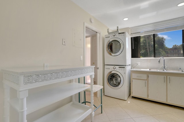 washroom featuring stacked washing maching and dryer, sink, and light tile patterned floors