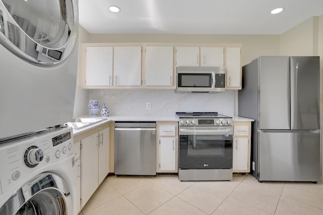 kitchen featuring backsplash, appliances with stainless steel finishes, light tile patterned flooring, and stacked washing maching and dryer