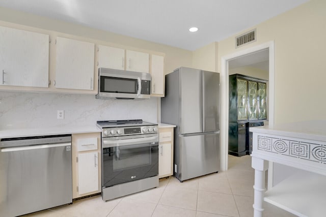 kitchen with decorative backsplash, appliances with stainless steel finishes, and light tile patterned flooring