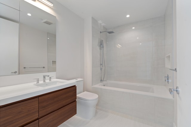 full bathroom with tiled shower / bath, vanity, and toilet