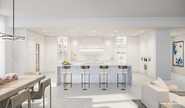 kitchen with white cabinets, premium range hood, hanging light fixtures, and a breakfast bar