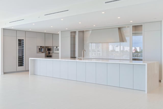 kitchen featuring gray cabinetry, a large island, and custom exhaust hood