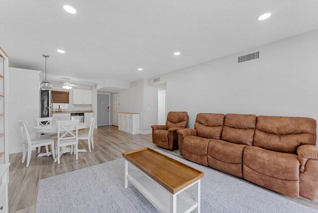 living room featuring light wood-type flooring, ceiling fan, and sink