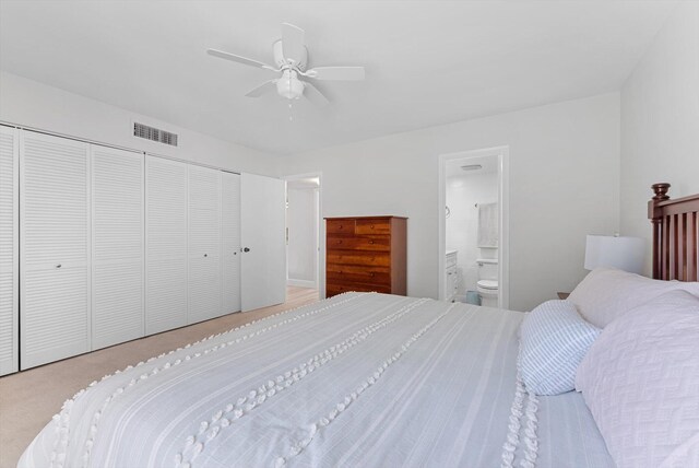 carpeted bedroom featuring ceiling fan, ensuite bathroom, and a closet