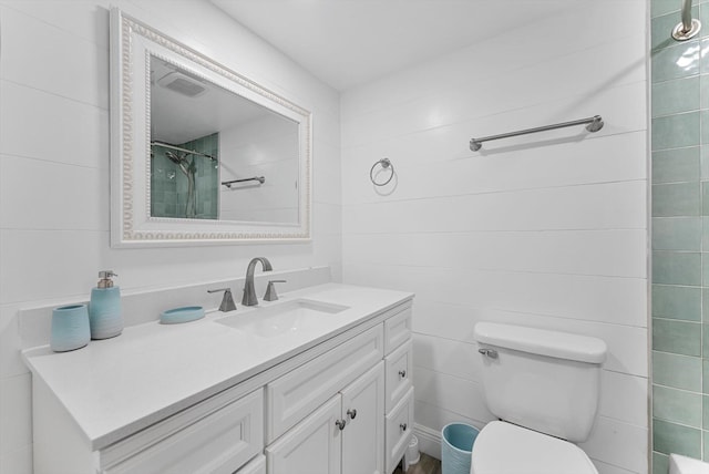 bathroom featuring vanity, toilet, and tiled shower