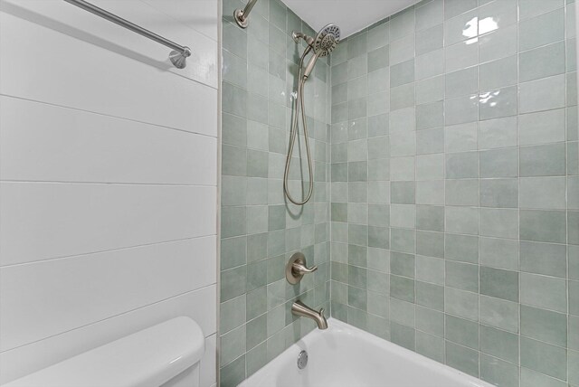 bathroom featuring tiled shower / bath and toilet