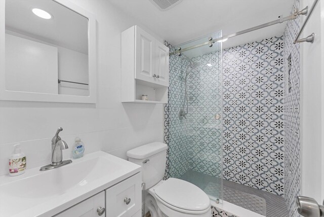 bathroom with tile walls, vanity, an enclosed shower, and toilet