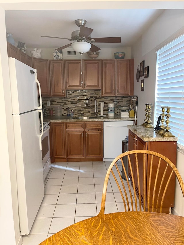 kitchen with tasteful backsplash, white appliances, light tile patterned floors, light stone countertops, and ceiling fan