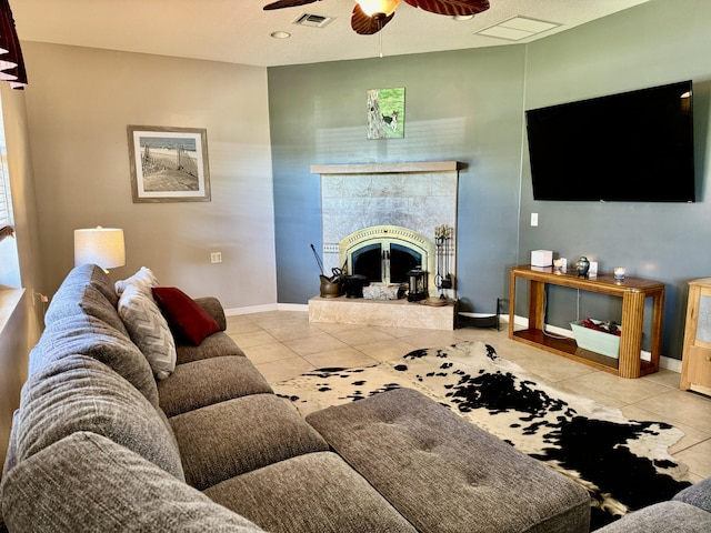 tiled living room featuring ceiling fan, a textured ceiling, and a tiled fireplace