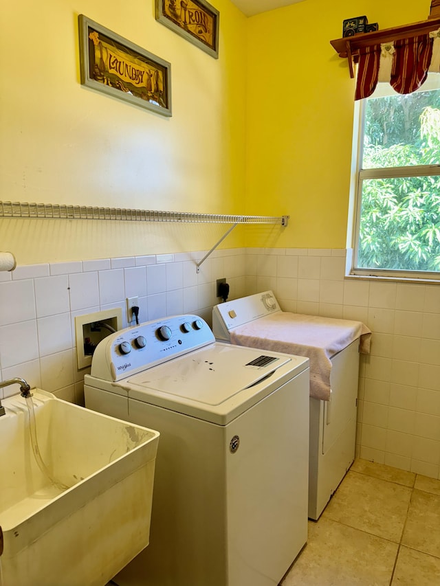 laundry area featuring tile walls, washer and dryer, and sink