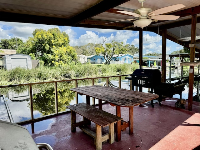 exterior space with ceiling fan, a water view, and a storage unit