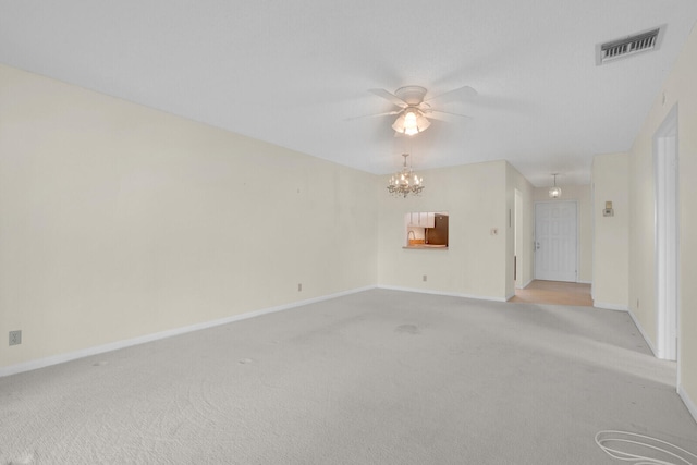 empty room featuring ceiling fan with notable chandelier and light colored carpet