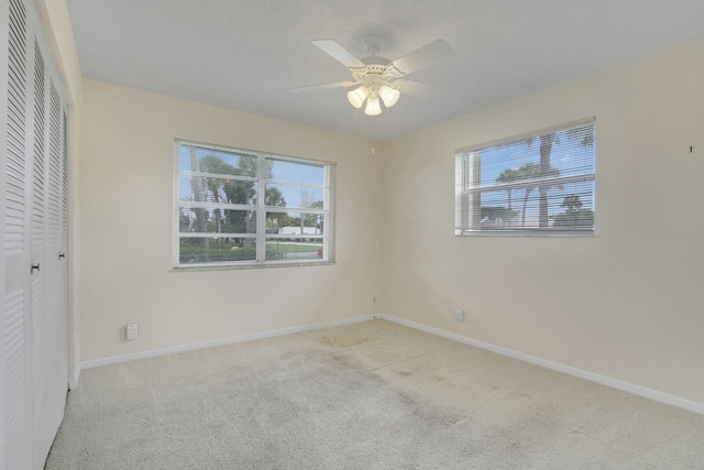 unfurnished room with light carpet, ceiling fan, and a wealth of natural light