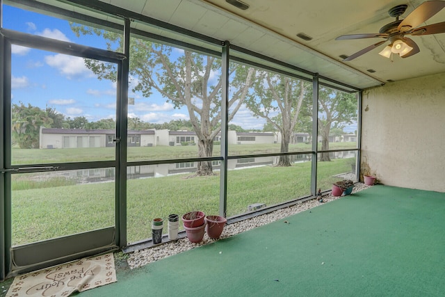 unfurnished sunroom featuring a healthy amount of sunlight, a water view, and ceiling fan