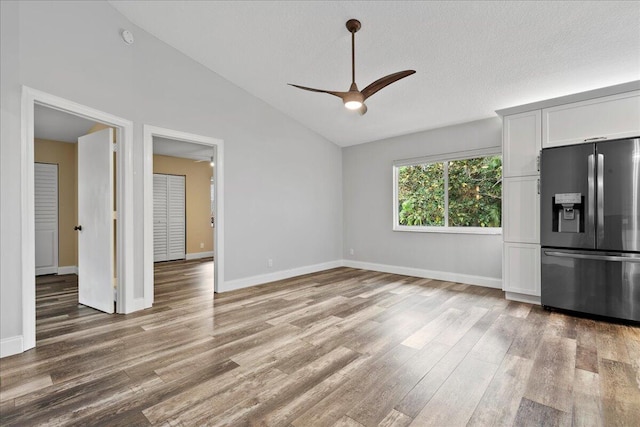 interior space with hardwood / wood-style flooring, high vaulted ceiling, ceiling fan, and a textured ceiling