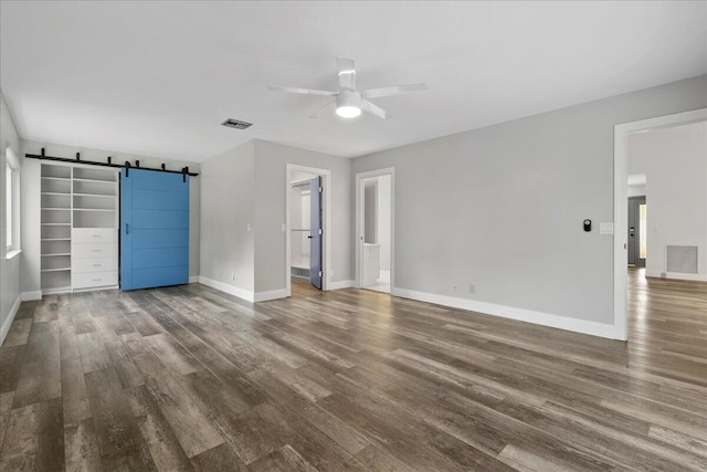 spare room with a barn door, dark hardwood / wood-style floors, and ceiling fan