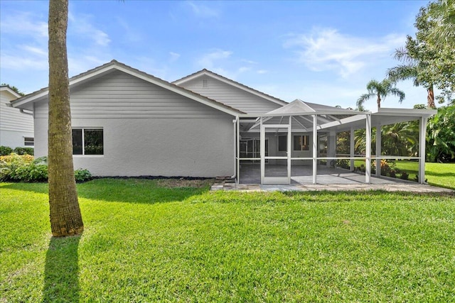 rear view of house with a patio area, glass enclosure, and a lawn