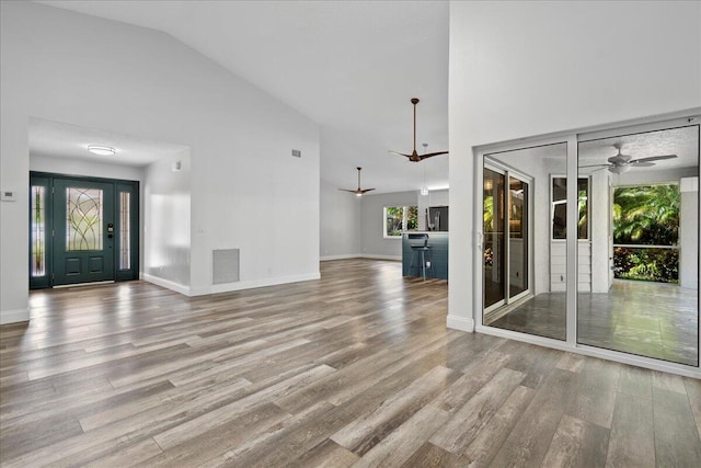 unfurnished living room featuring high vaulted ceiling, light wood-type flooring, and ceiling fan