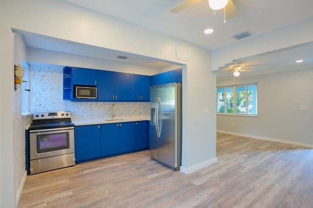 kitchen featuring ceiling fan, tasteful backsplash, blue cabinetry, stainless steel appliances, and light hardwood / wood-style floors