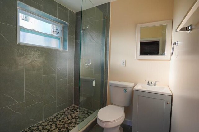 bathroom with a shower with door, vanity, and toilet