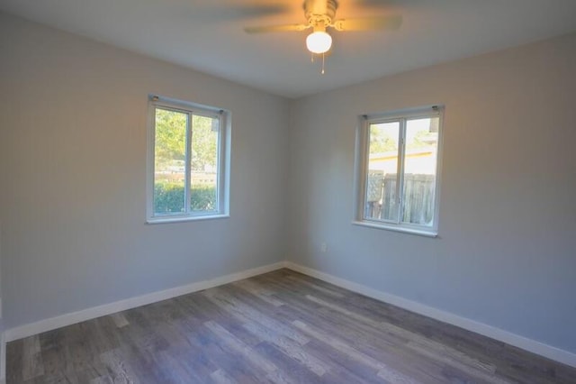 spare room featuring ceiling fan, a healthy amount of sunlight, and dark hardwood / wood-style flooring