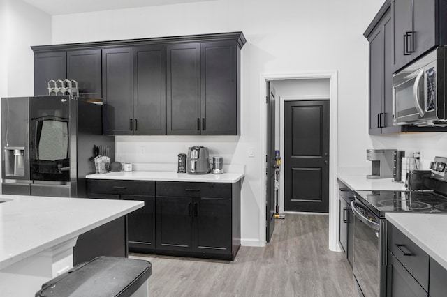 kitchen with light stone counters, light hardwood / wood-style floors, and appliances with stainless steel finishes