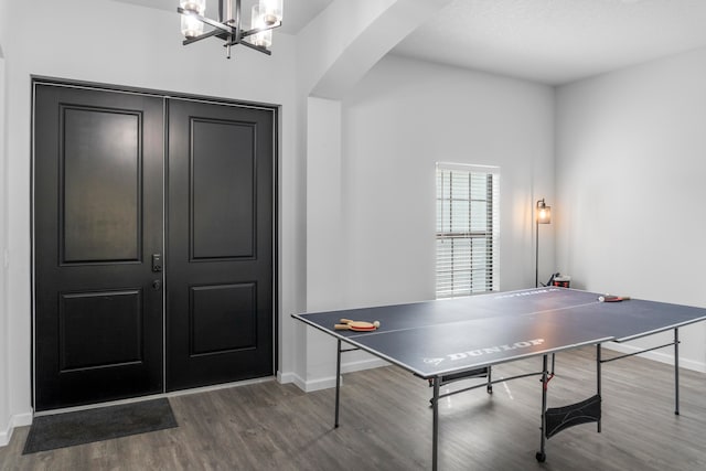 recreation room with a chandelier and dark wood-type flooring