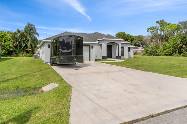 view of front of home featuring a garage, cooling unit, and a front lawn