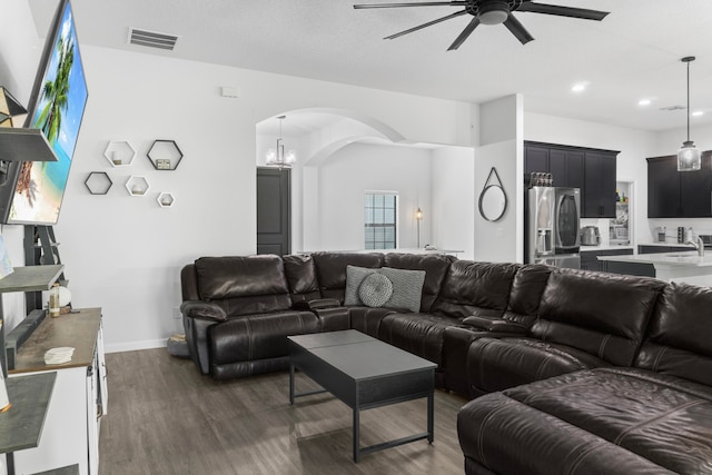 living room with ceiling fan with notable chandelier, dark hardwood / wood-style floors, and sink