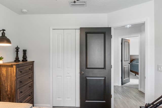 bedroom with a textured ceiling, light hardwood / wood-style flooring, and a closet