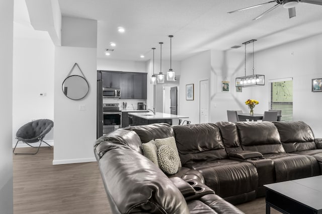 living room featuring ceiling fan with notable chandelier, dark hardwood / wood-style floors, and sink