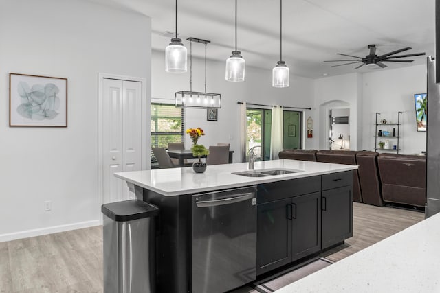 kitchen featuring an island with sink, sink, decorative light fixtures, and stainless steel dishwasher