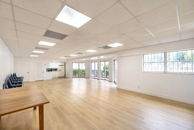 unfurnished living room featuring a paneled ceiling and light hardwood / wood-style flooring