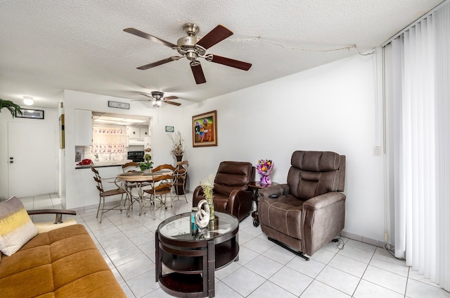 living room with ceiling fan, a textured ceiling, and light tile patterned floors